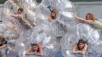Frauen in aufblasbaren Bällen auf einem Platz.
