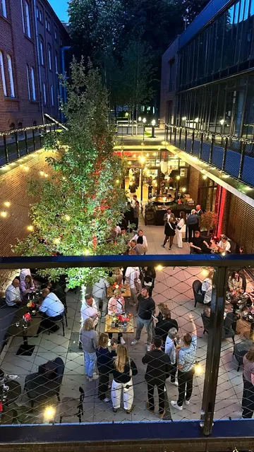 People gathered in outdoor courtyard, evening lights.