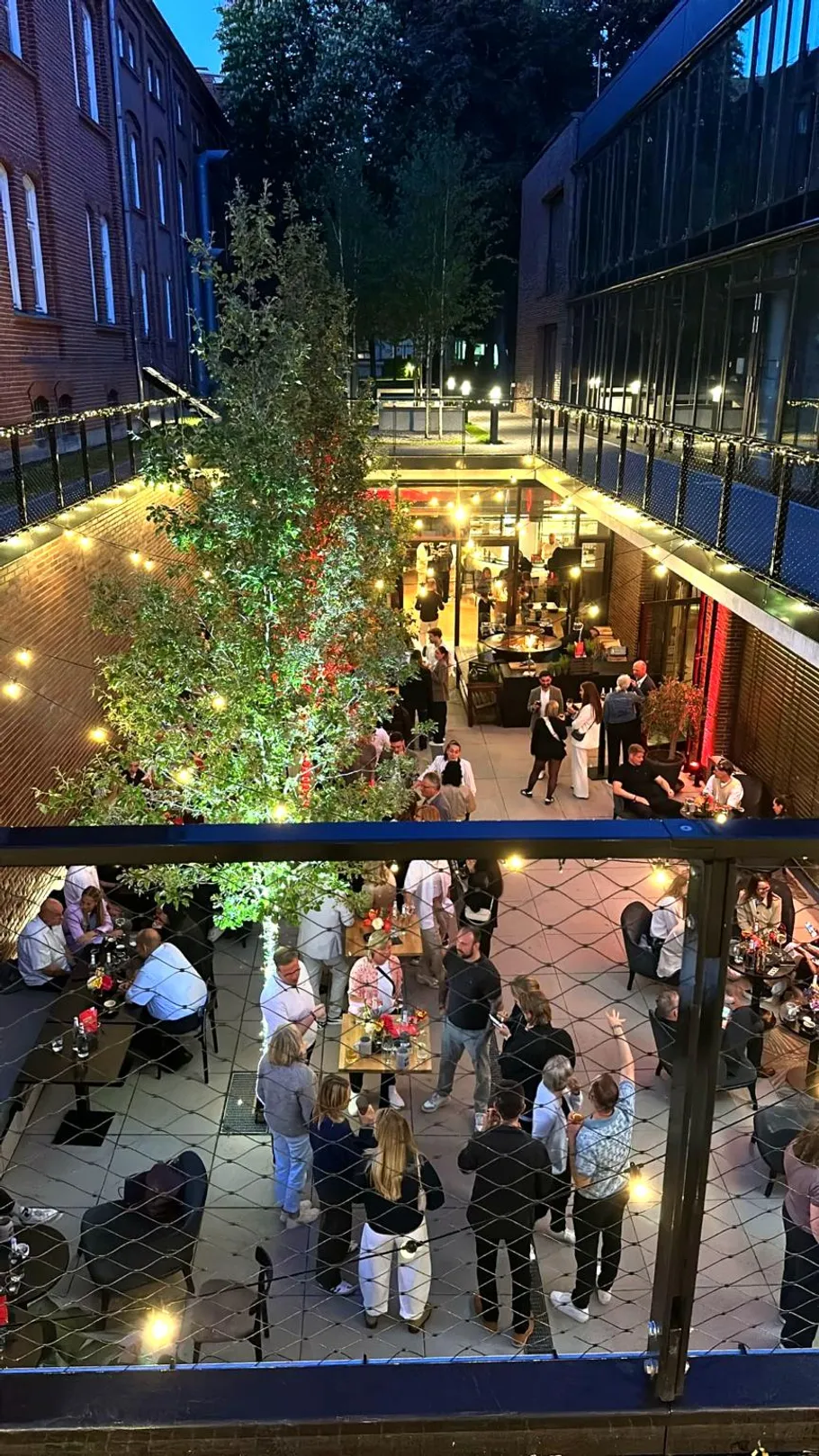 People gathered in outdoor courtyard, evening lights.