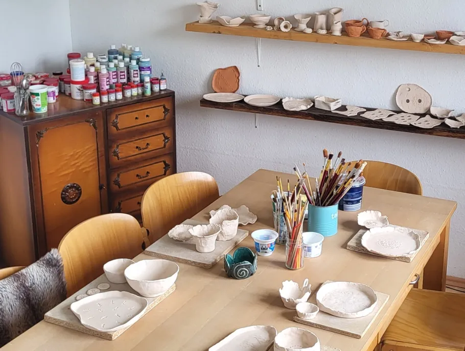 Pottery studio with tools and painted ceramics.