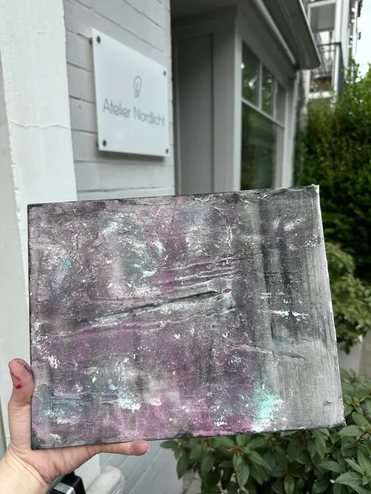 Hand hält abstraktes Gemälde vor Kunststudio.