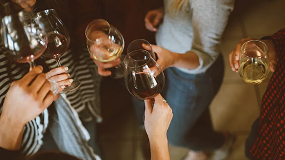 People clinking wine glasses at a gathering.
