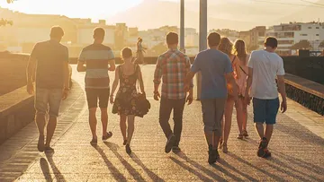 People walking on sunlit path in city.