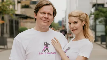 Two people posing with matching dance shirts.