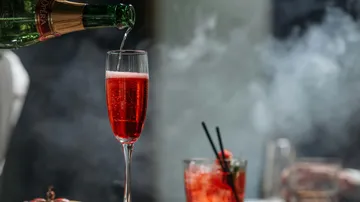 Rotes Getränk in Champagnerglas gegossen.