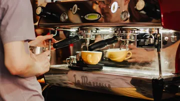Barista bereitet Kaffee mit Espressomaschine zu.