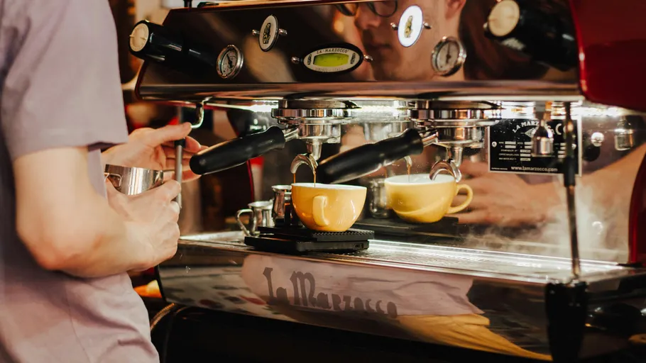Barista prepares coffee using espresso machine.