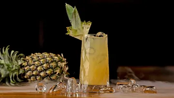 Ananas-Cocktail mit Eis und Obst im Hintergrund.