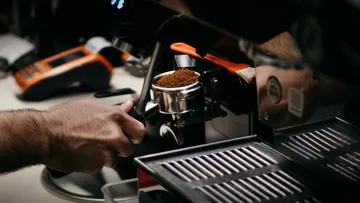 Barista preparing coffee with espresso machine.