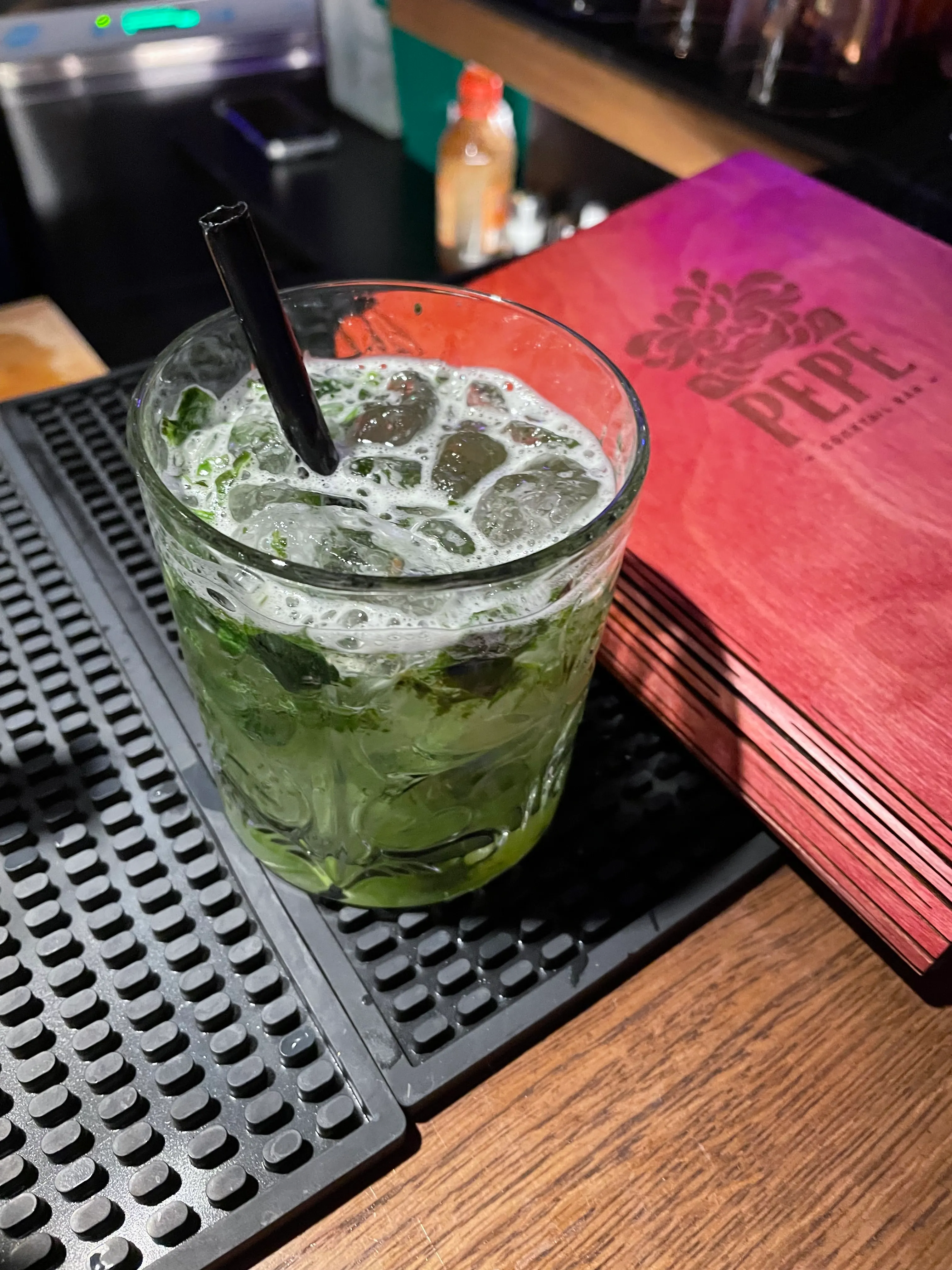 Mint cocktail with straw on bar counter.