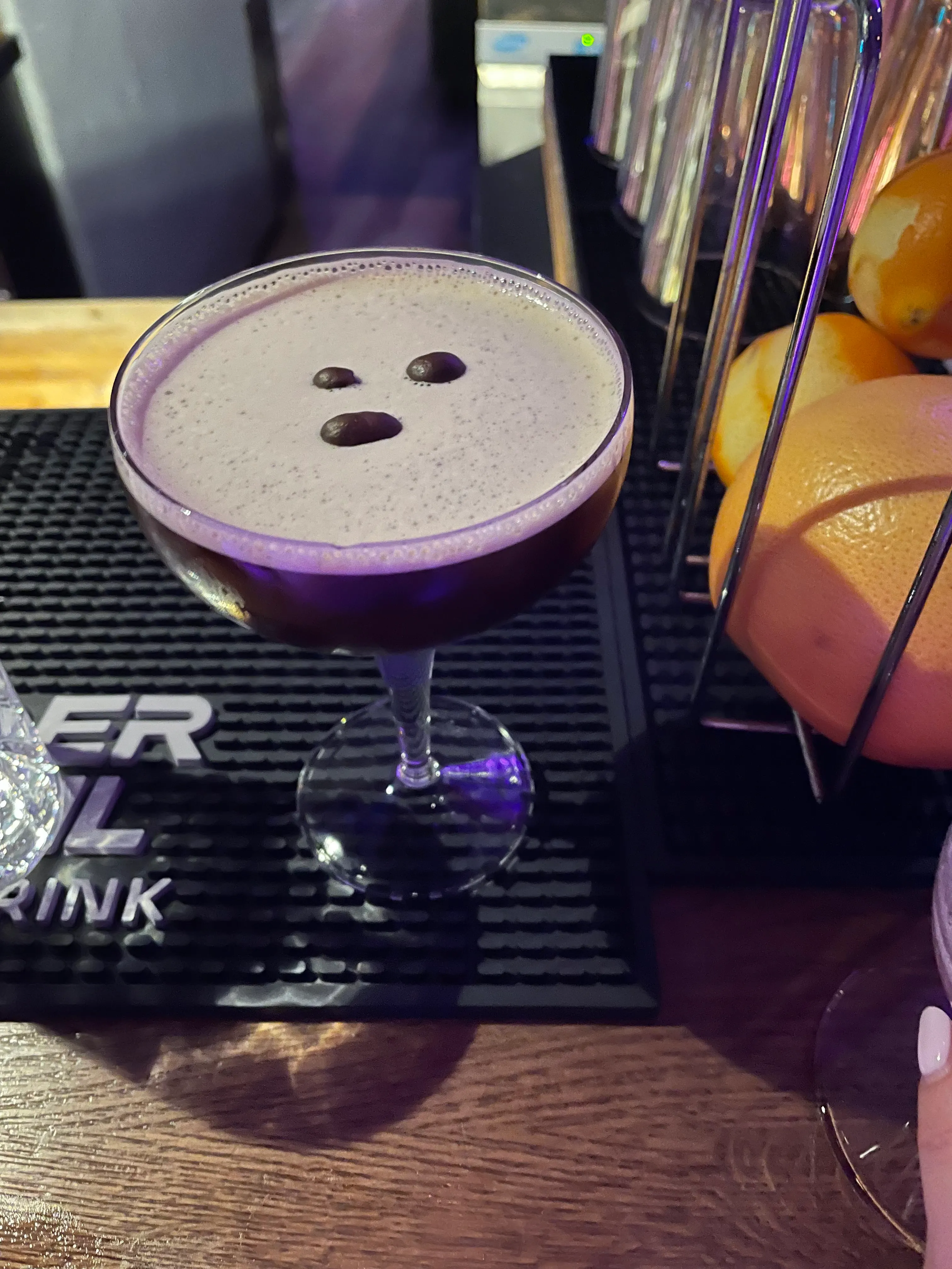 Espresso martini on bar with lemons nearby.