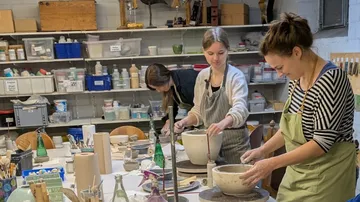 People crafting pottery in a studio setting.
