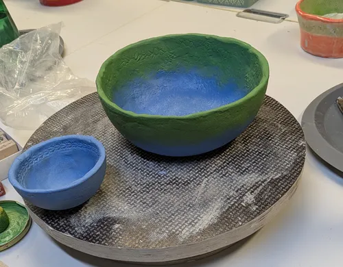 Two painted bowls on a textured surface.