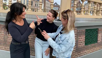 Three women laughing and pointing outside.