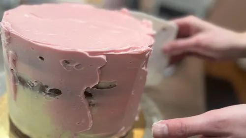 Hände glasieren Kuchen mit rosa Zuckerguss.