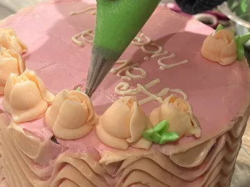 Kuchenverzierung mit rosa Zuckerguss und Rosendekor.
