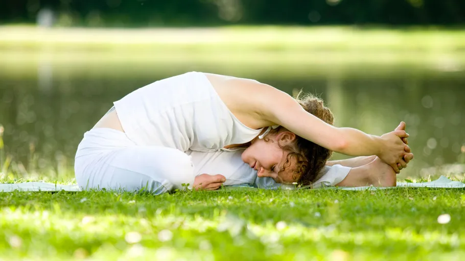 Person doing yoga stretch by a lake.