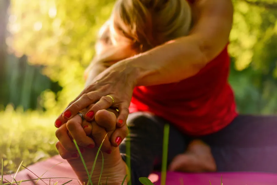Person stretching on yoga mat outdoors.