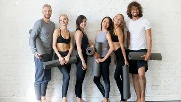 Gruppe mit Yogamatten vor Ziegelwand.