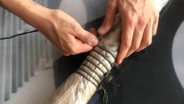 Hands wrapping twine around a bundled object.
