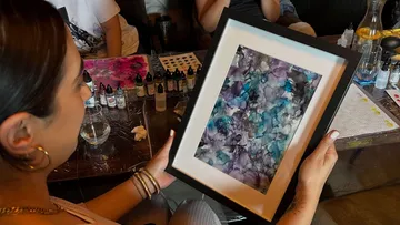 Person holding framed abstract artwork indoors.