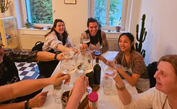 Menschen stoßen mit Wein an einem Tisch an.