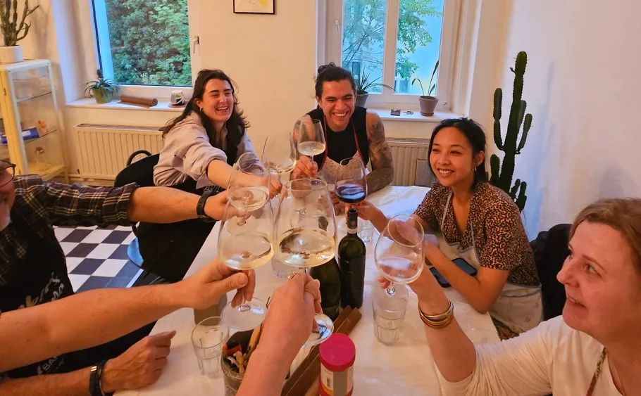 Menschen stoßen mit Wein an einem Tisch an.