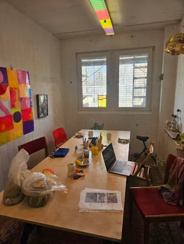 Art studio table with supplies and laptop.