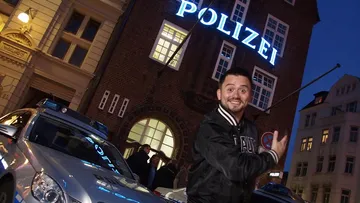 Man gesturing excitedly outside police station.