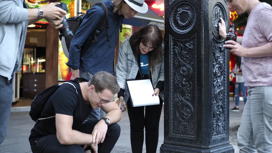 People examining a decorative pillar on the street.