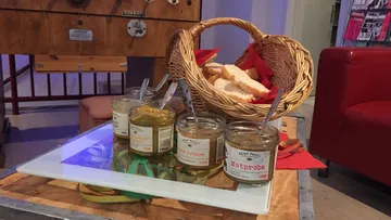 Senfgläser neben Brotkorb auf Tisch.