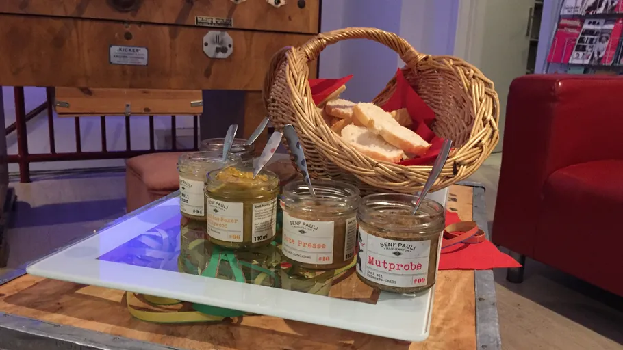 Senfgläser neben Brotkorb auf Tisch.