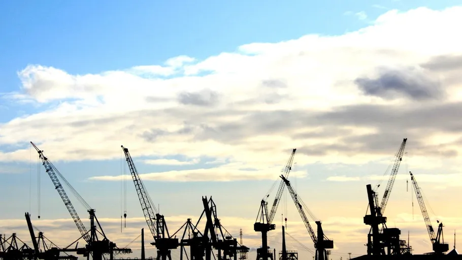 Cranes silhouetted against a cloudy sky.