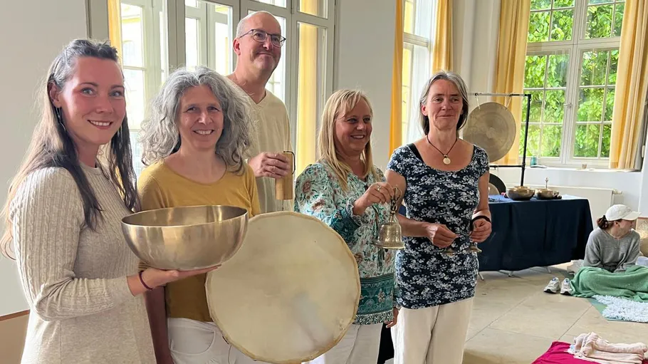 Five people holding musical instruments indoors.