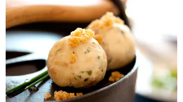 Zwei Knödel mit Semmelbröseln in Pfanne.