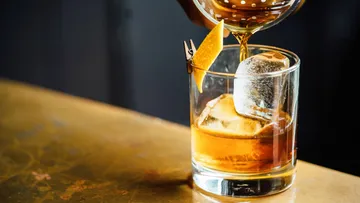 Whiskey being poured into a glass with ice.