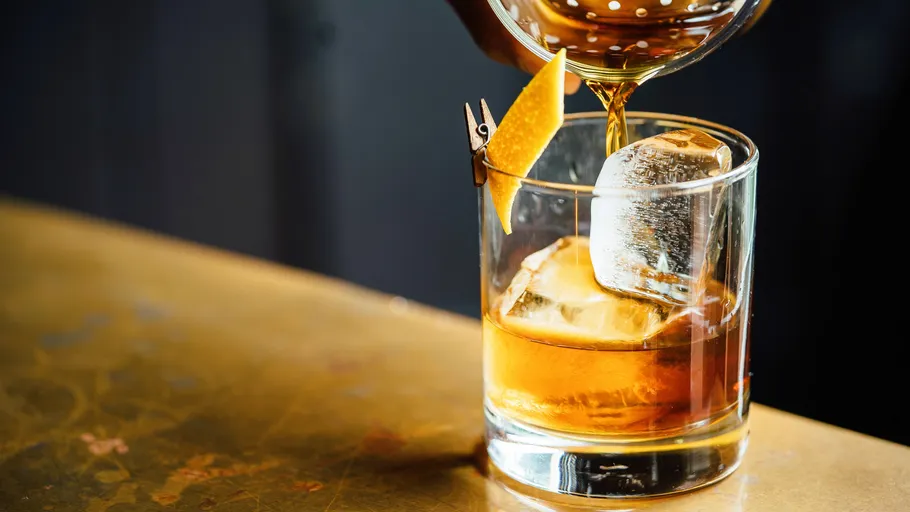 Whiskey being poured into a glass with ice.