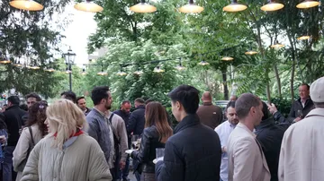People socializing outdoors under string lights.