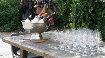 Table with wine bottles and glasses outdoors.