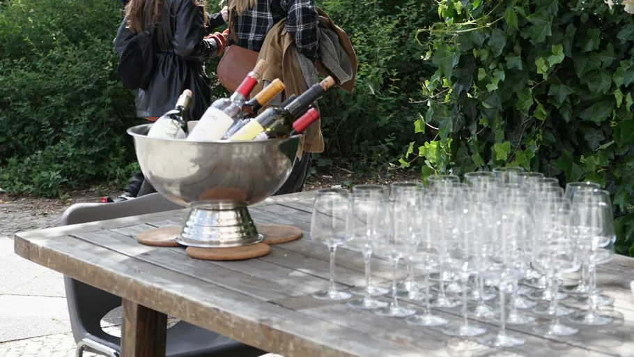 Table with wine bottles and glasses outdoors.