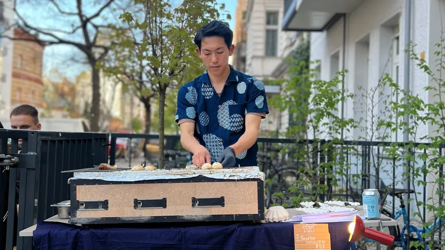 Man cooking on outdoor stovetop in urban setting.