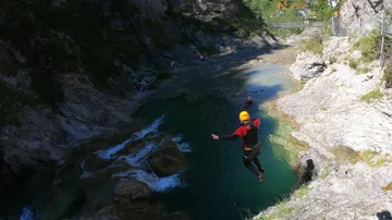 Person jumping into mountain river gorge.