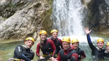 Personen in Neoprenanzügen am Wasserfall.