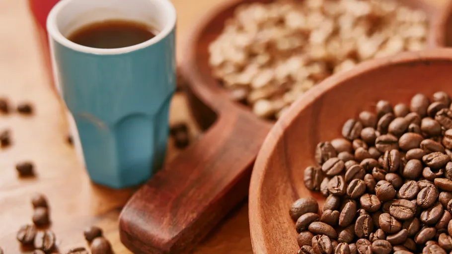 Coffee cup beside roasted coffee beans bowl.