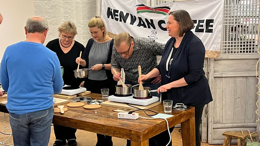 Group cooking at table, Kenyan coffee banner.