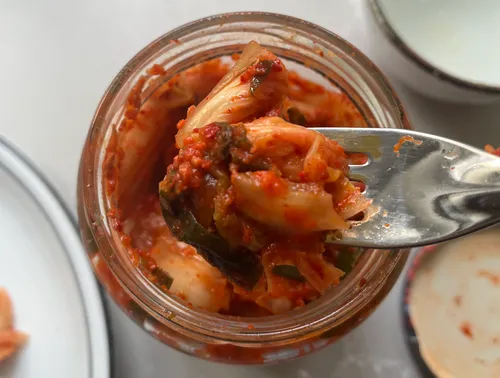Gabel hebt Kimchi aus einem Glas.