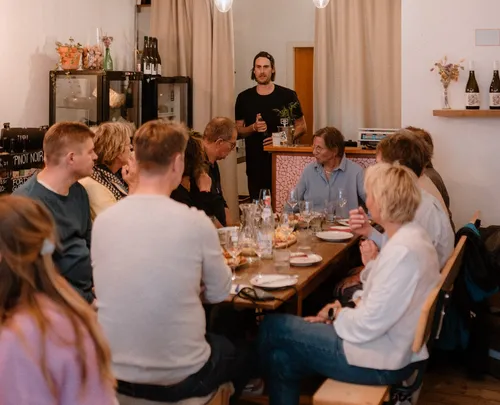 Gruppe versammelt sich am Tisch, Redner spricht.
