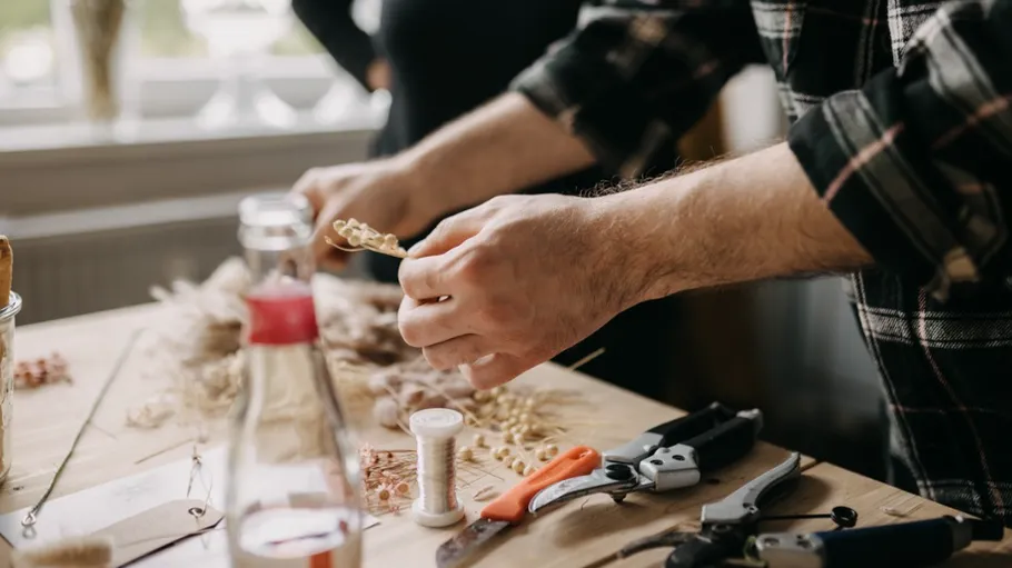 Hands crafting with tools on wooden table.