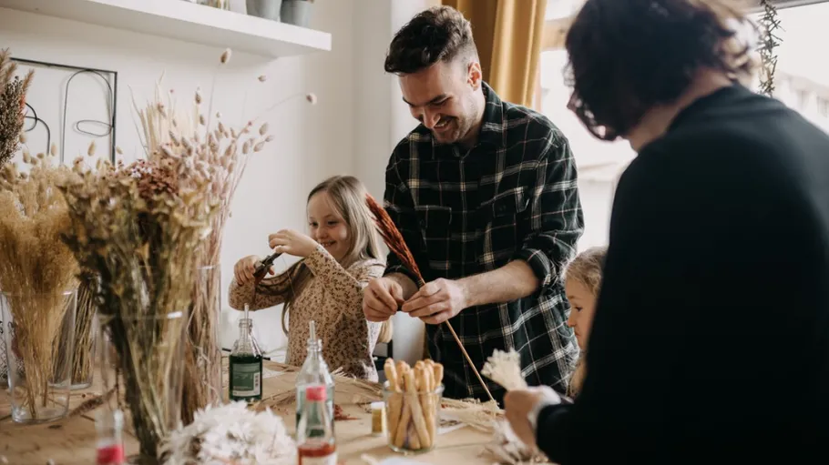 Family crafting with dried flowers at the table.