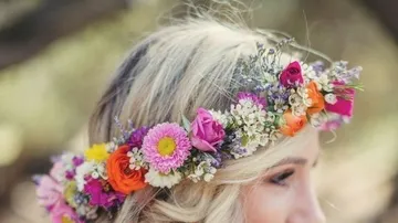 Floral crown adorns woman's blonde hair outdoors.